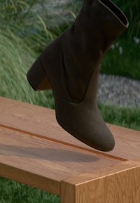 Braune Wildlederstiefelette mit spitzem Zehenbereich und blockartigem Absatz, die über eine glatte Textur und ein elegantes, minimalistisches Design verfügt.