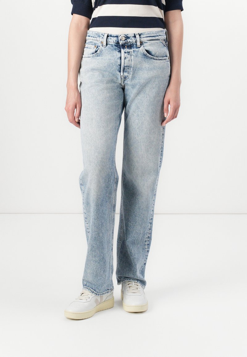 Lichtblauwe, rechtengesneden jeans van denim, met een vervaagde textuur, vijf zakken en een rits. Draag ze met witte sneakers.