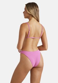 Růžová bikiny vršek s tenkými ramínky a nastavitelným kováním; odpovídající vysoko pasové spodní části mají hladkou texturu a minimalistický design.