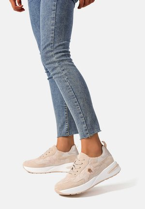 Sneaker beige con tomaia in suede e mesh, con sottili motivi circolari e suola bianca. Indossati con jeans skinny azzurri chiari, con orlo sfrangiato.