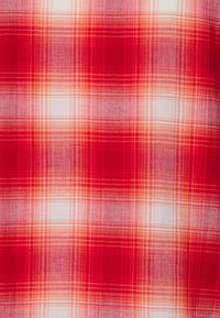 Czerwona i biała sztruksowa tkanina w kratkę z przecinającymi się poziomymi i pionowymi liniami tworzącymi kwadraty oraz tkanym wzorem.
