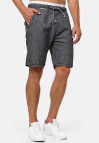 Mænds mørkegrå shorts lavet af tekstureret stof. Har en elastisk talje med snor og sidelommer. Bæres med hvide sneakers.