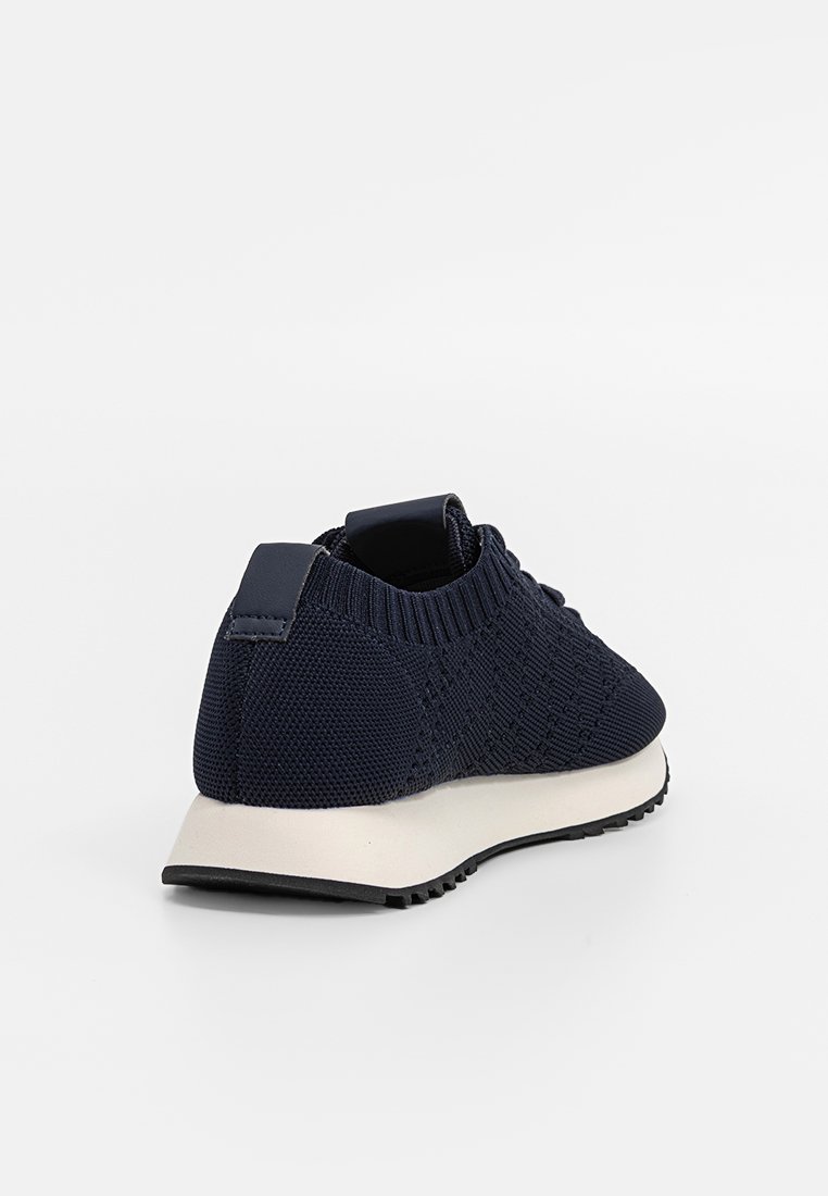 Dunkelblaue Strick-Sportschuh mit strukturiertem Obermaterial, runder Zehenpartie und weißer Gummisohle. Verfügt über ein strukturiertes Muster und einen gepolsterten Kragen.