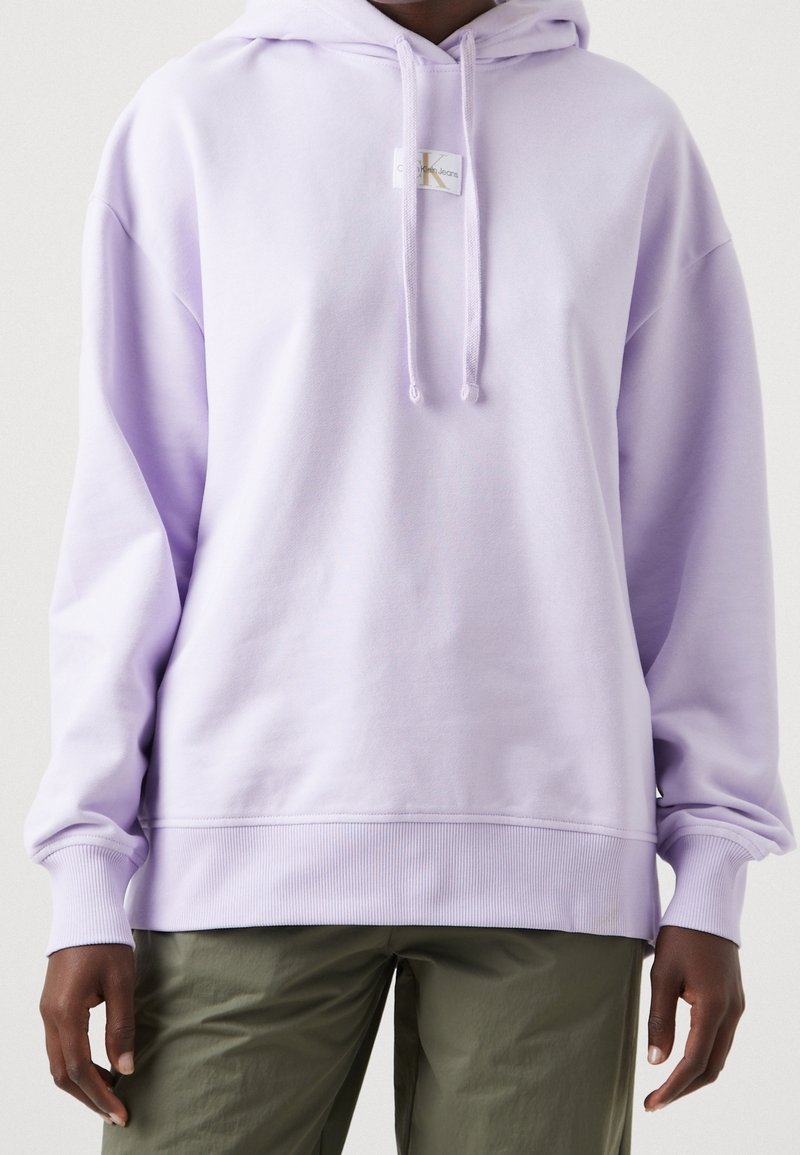 Felpa leggera color lavanda con vestibilità comoda, dotata di tasca frontale a marsupio, cordini e un piccolo etichetta logo. Materiale in cotone morbido.