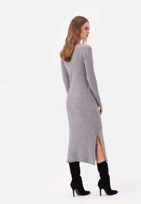 Szara, prążkowana dzianinowa sukienka z długimi rękawami i bocznym rozcięciem, w połączeniu z czarnymi, zamszowymi botkami na obcasie do kolan. Gładka faktura. Prosty wzór.