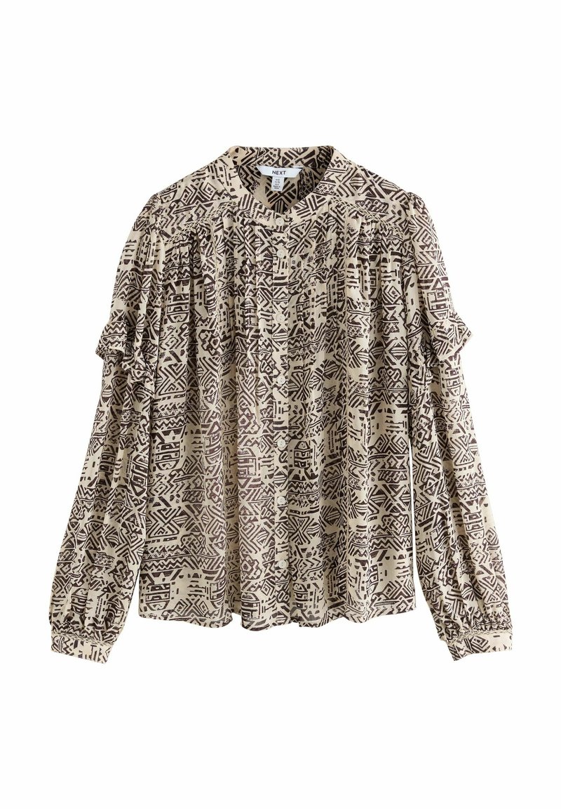 Blouse beige à manches longues avec motifs géométriques abstraits noirs, boutonnée devant, avec des détails froncés aux épaules et aux poignets.