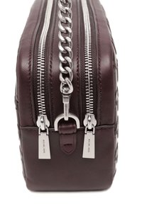 Borsa in pelle bordeaux con dettagli in catena argento e doppie cerniere. Presenta una superficie testurizzata e accentuazioni del logo vicino ai tiranti delle cerniere.