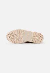 Suola di sneaker in gomma color crema con texture a righe e motivo a cinque stelle. Presenta il marchio "ESPRIT" impresso nella zona del tallone.