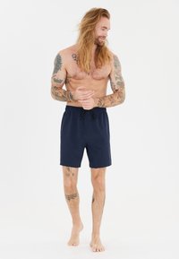 Meripihkavyöttiivä uimapuku tummansinisestä väristä, jossa on joustava vyötärö ja musta naru. Valmistettu sileästä kankaasta, polvipituinen ja yksinkertainen muotoilu.