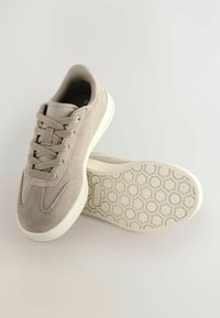 Lys grå ruskinds sneakers med snørrelukning, polstret krave og struktureret gummisål med honningkage mønster.