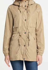 Beige lehká bunda s staženým pasem, nastavitelnými šňůrkami, kapucí a patentkami. Obsahuje boční kapsy na zip a elastické manžety.