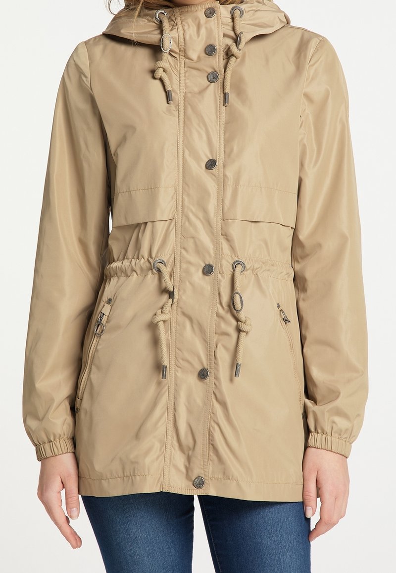 Beige lehká bunda s staženým pasem, nastavitelnými šňůrkami, kapucí a patentkami. Obsahuje boční kapsy na zip a elastické manžety.