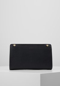 Svart rektangulär handväska av texturerat material. Har guldtonade detaljer vid övre hörnen, minimalistisk design och ingen synlig hårdvara.