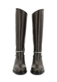 Stivali alti in pelle marrone con punta arrotondata, texture liscia e dettagli in metallo argentato alla caviglia. Suola piatta e design elegante.