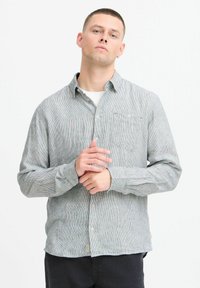 Gray and white striped button-up shirt with a collar, featuring a chest pocket and long sleeves, made from a textured fabric.