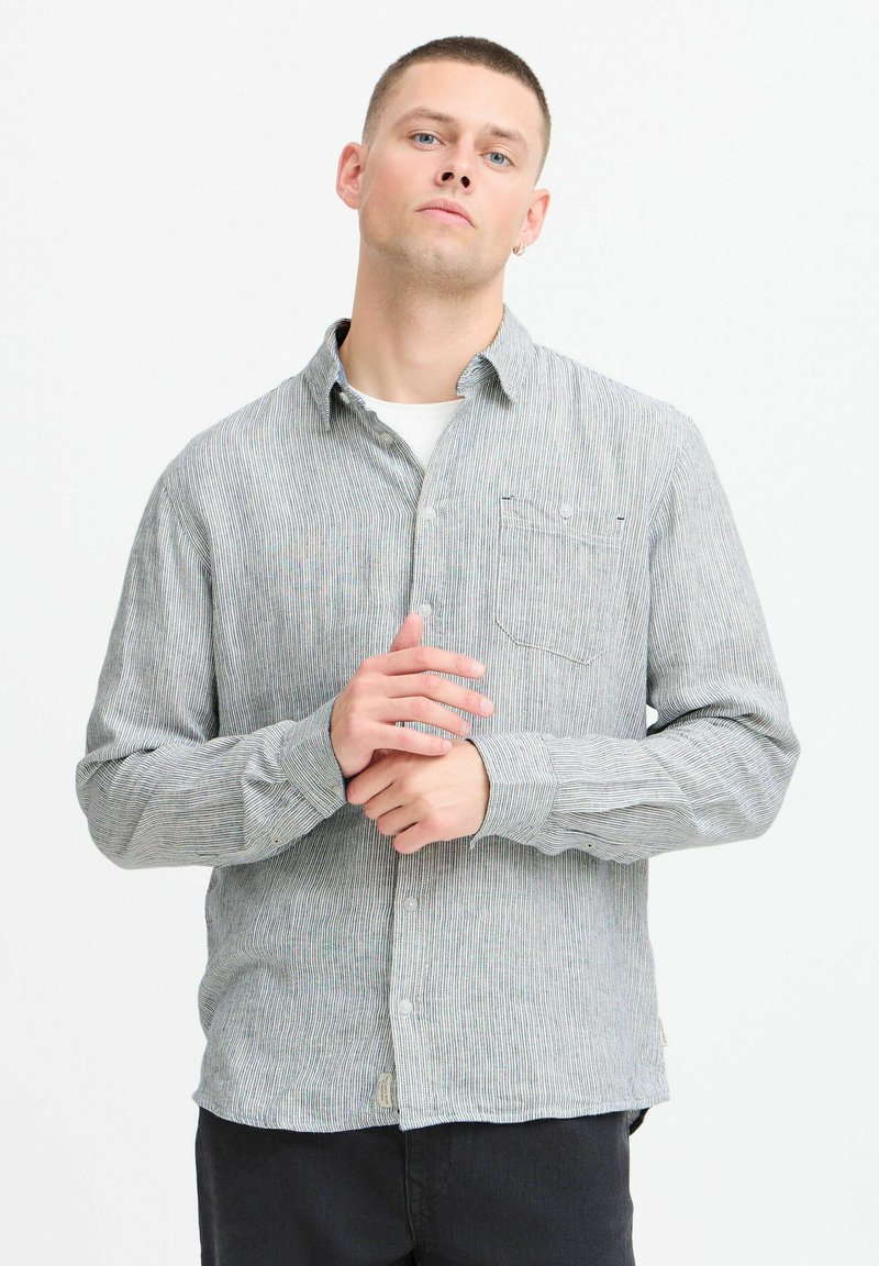 Gray and white striped button-up shirt with a collar, featuring a chest pocket and long sleeves, made from a textured fabric.