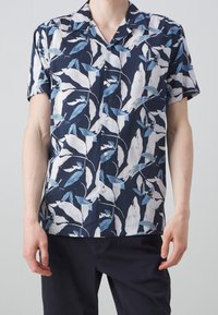 Košile s krátkým rukávem s knoflíky, která má námořnické pozadí s bílými a modrými vzory listů, vyrobená z lehkého materiálu. Standardní design límce.