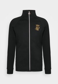 Giacca nera con zip in tessuto morbido. Presenta un colletto alto, maniche lunghe e un logo ricamato in oro sulla parte sinistra del petto.