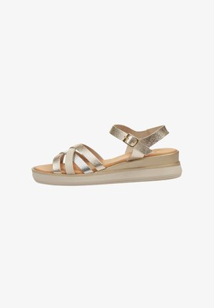 Sandalias con tiras y un acabado metálico dorado, que cuentan con una correa ajustable en el tobillo, una suela acolchada y una base de plataforma de color beige claro.