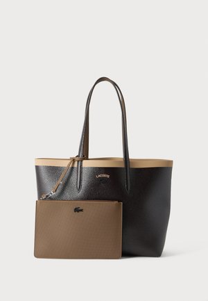 Black textured tote bag with beige trim and handles, featuring a matching brown zippered pouch attached by a strap with Lacoste logos.