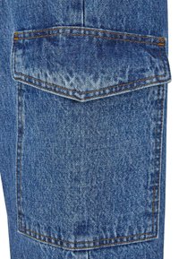 Poche en tissu denim bleu avec rabat et couture orange sur un jean ou un vêtement en denim.