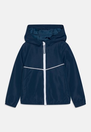 Chaqueta impermeable azul marino con capucha, cremallera blanca y una franja horizontal blanca en el pecho. Textura lisa, material ligero.