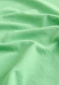 Svijetlozeleni materijal s mekom, glatkom teksturom, koji sadrži suptilne nabore i bore koje poboljšavaju njegovo draperanje i fleksibilnost.
