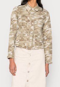 Camo-patterned, fitted denim jacket in beige tones with a button-up front, frayed edges, and two chest pockets. Long sleeves with cuff detail.