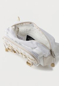 Λευκή τσάντα μέσης North Face με δύο φερμουάρ σε διαμερίσματα, μπεζ λεπτομέρειες και εσωτερική τσέπη από δίχτυ που φαίνεται μέσω του ανοιχτού κεντρικού φερμουάρ.