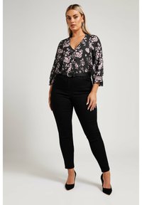 Svart blommig blus med rosa mönster, V-ringning och trekvartslånga ärmar. Matchas med hög midja svarta jeans och svarta högklackade skor.