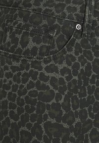 Jeans con estampado de leopardo negro y verde que cuentan con un bolsillo trasero y costuras en contraste, fabricados con una tela de denim texturizada.