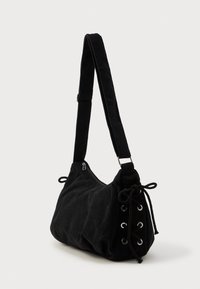 Borsa a tracolla in corduroy nero con forma arrotondata, tracolla regolabile, chiusura con zip e dettaglio in cordoncino laterale con occhielli metallici.