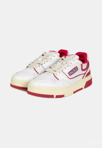 Sneakers bianche con accenti rossi, in materiale pelle, suola in gomma testurizzata, tomaia perforata per la traspirabilità e un logo prominente.