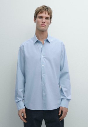 Camicia azzurro chiaro con bottoni, realizzata in tessuto liscio, con maniche lunghe, colletto classico e orlo diritto, con bottoni bianchi.