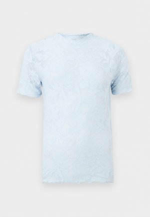 Top bleu deschis cu mâneci scurte, model floral subtil în relief și decolteu rotund pe fundal simplu.