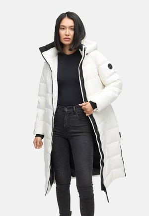 Cappotto imbottito bianco con interno e dettagli neri. Include un cappuccio, maniche lunghe e zip frontale. Indossato sopra un top nero e jeans scuri.
