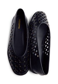 Bailarinas de cuero negro con un diseño trenzado, tachuelas doradas y un interior suave. Punta redondeada y perfil bajo, con estilo de calzado sin cordones.