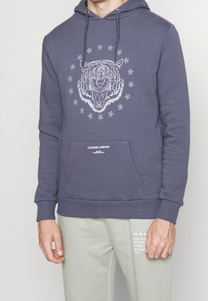 Navy hoodie featuring a tiger graphic, star accents, drawstring hood, and front pocket. Text at the hem reads "CLOSURE LONDON."