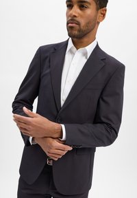 Donkerblauwe blazer van gladde stof, met een enkele knoopsluiting, gestructureerde schouders en een slank ontwerp met zakdetails.