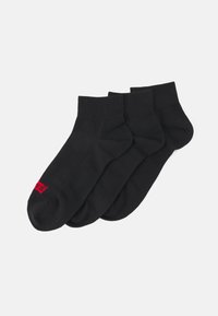 Svarta ankelsockor i mjukt bomullsmaterial, med ribbad kant och subtil röd logotyp på sidan. Tre par visas.