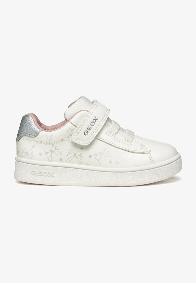 Basket blanche pour enfants avec motifs de nœuds argentés, doublure intérieure rose, patch argenté au talon et bride velcro étiquetée "GEOX".