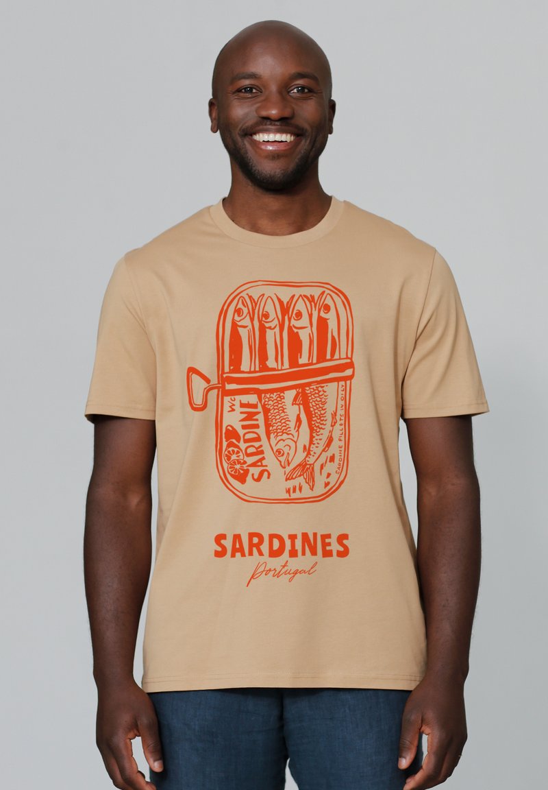Beige T-Shirt mit einem grauen Fischerboot, das in der Mitte des Shirts abgebildet ist. Darunter sind Fische und das Wort "SARDINES Portugal" auffällig dargestellt.