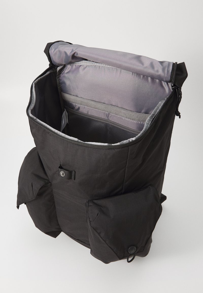 Sac à dos noir avec un design à enroulement, intérieur gris, multiple compartiments et poches avant fermées par des boutons. Finition en tissu texturé.