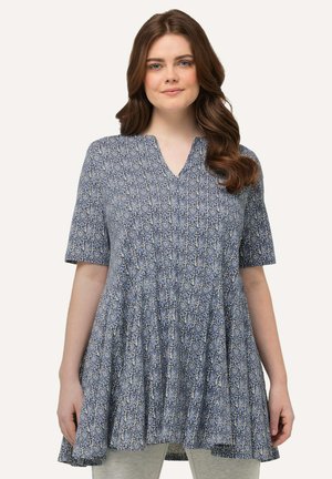 Niebieska tunika w wzory z krótkimi rękawami, dekoltem w kształcie v, zwiewnym dołem i miękką teksturą. Design charakteryzuje się misternymi motywami w kolorze kremowym i granatowym.
