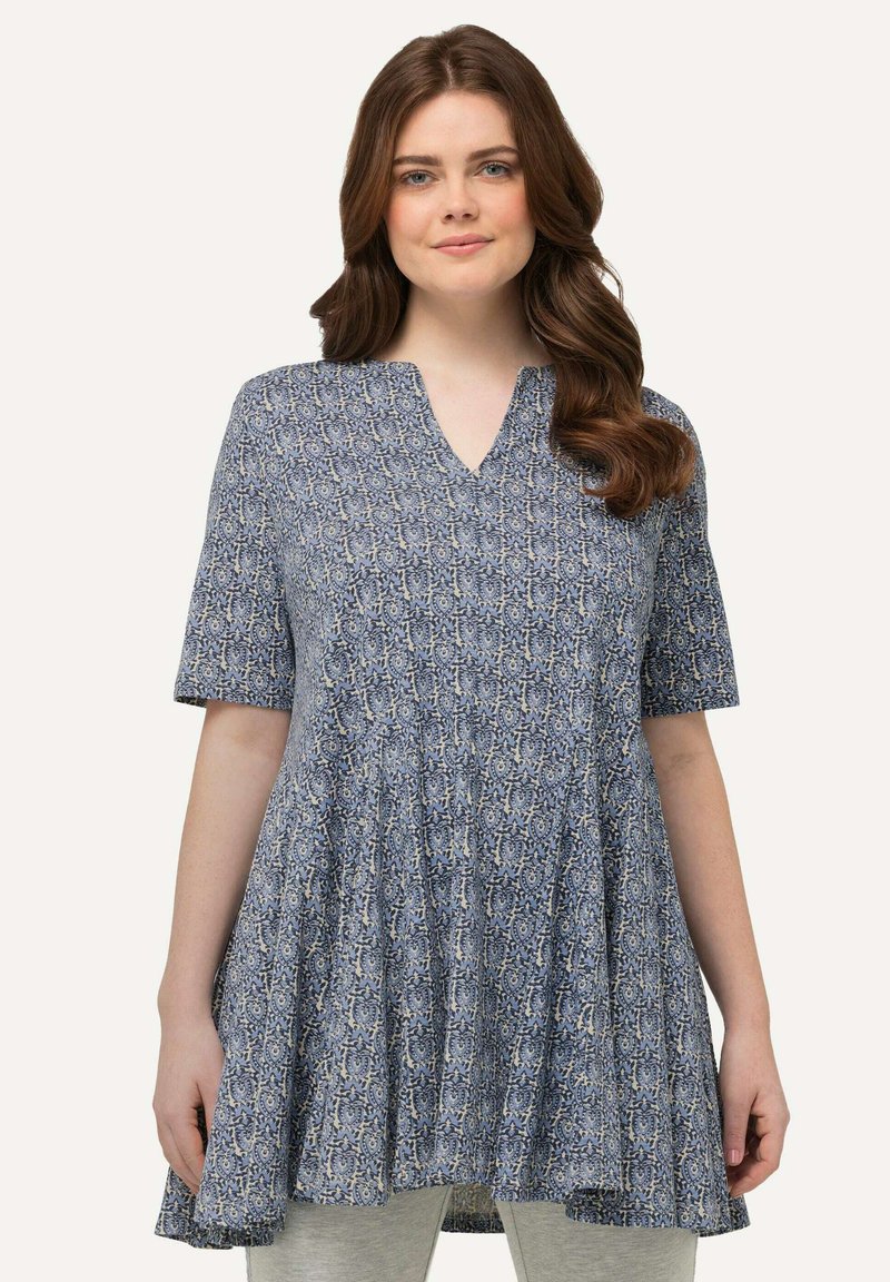 Tunic blu con motivo, maniche corte, scollatura a V, orlo fluido e una texture morbida. Il design presenta motivi intricati in crema e blu navy.