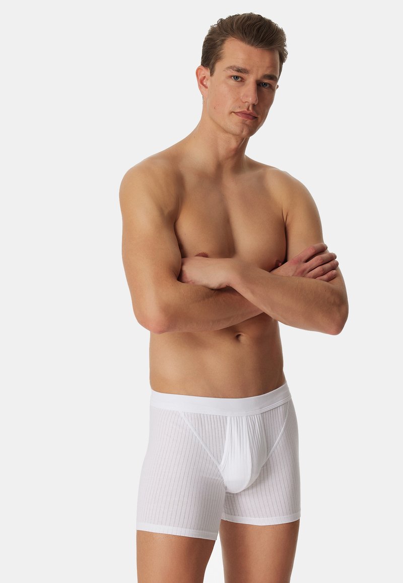 Bílé žebrované pánské boxerky z lehkého materiálu, s měkkým pasem a tvarovanou kapsou pro podporu.