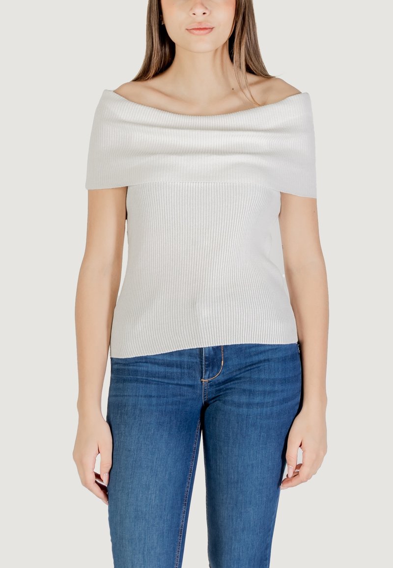 Top a spalle scoperte, a costine, di colore grigio chiaro. Texture liscia con un design aderente. Abbinato a jeans blu, con dettagli minimi e senza hardware visibile.