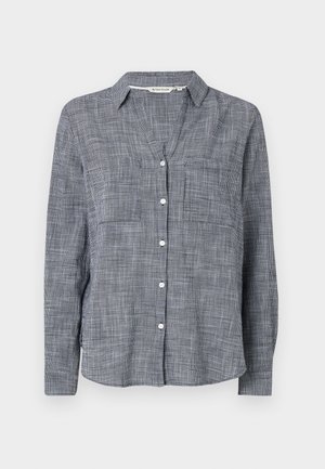 Chemise à boutons en tissu à carreaux navy et blanc, avec un col, deux poches poitrine et des manches longues avec des poignets à boutons.