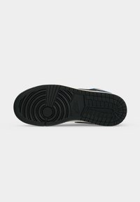 Σόλα μαύρου αθλητικού παπουτσιού Nike με κυκλικό μοτίβο πέλματος στο μπροστινό μέρος και ορθογώνιες αυλακώσεις στη φτέρνα σε λευκό φόντο.