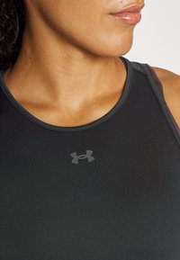 Svart sportstopp med en kroppsnära design, tillverkad av mjuk, elastisk tyg, med en grå logotyp på bröstet och tunna axelband.